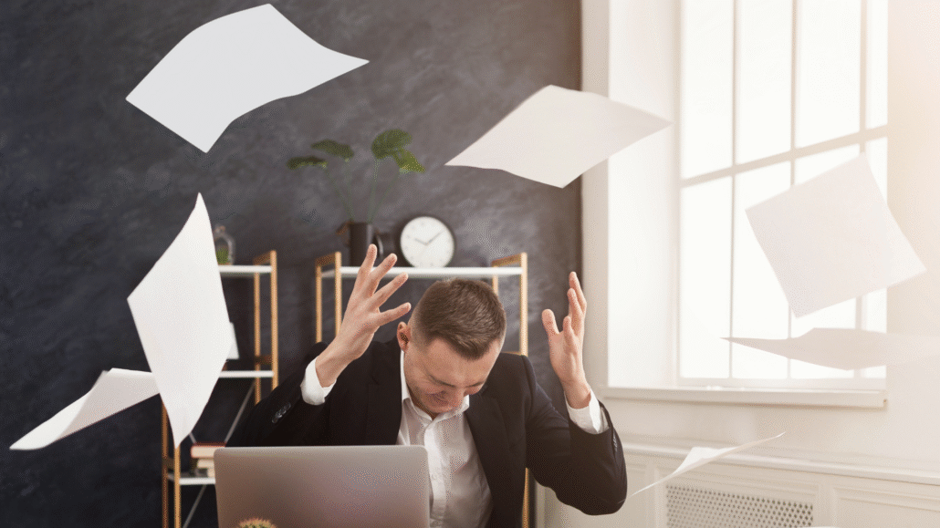 An operations manager looking overwhelmed by the chaotic paperwork of a traditional manual inventory process.